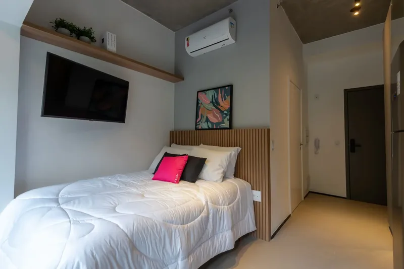Bed of the decorated studio with Housi linen and a television on the wall