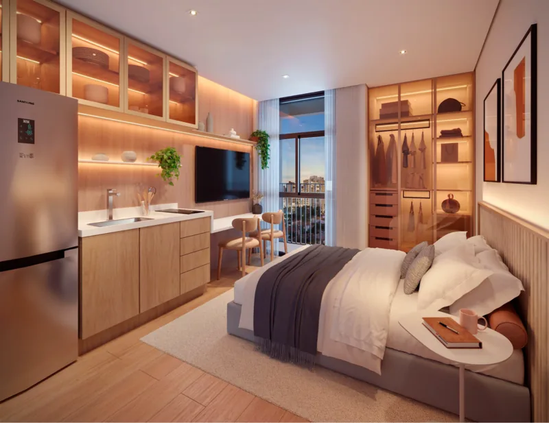 Interior of a compact studio with bed, work desk, integrated kitchenette and a wide window