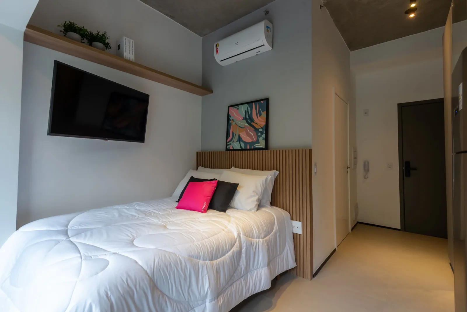 Bedroom of the furnished studio with Housi linens and wall-mounted TV