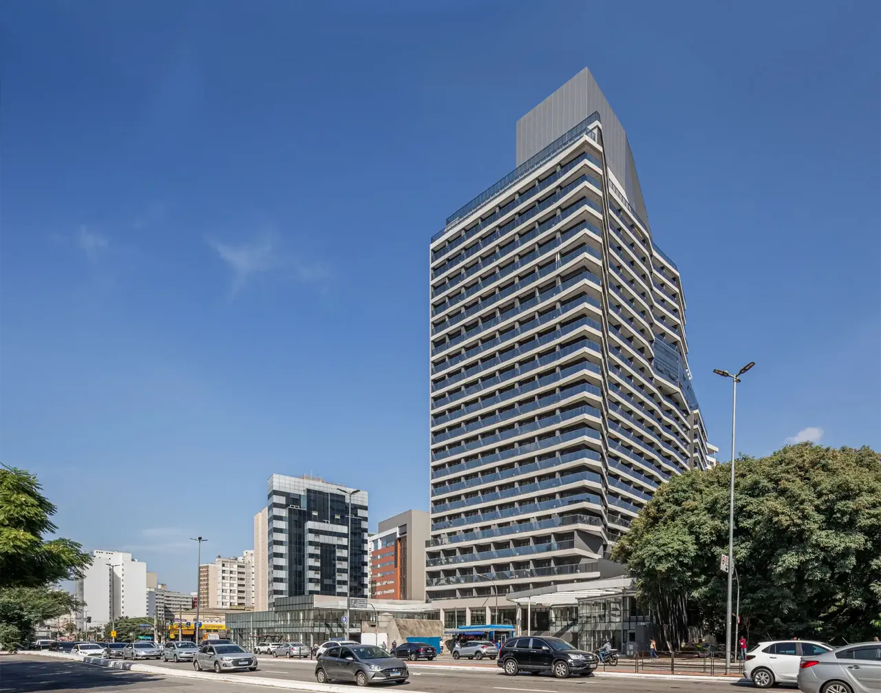 Real facade of ON Paulista: tower with undulating balconies under a blue sky, seen from the avenue